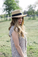 Portrait of a beautiful elegant woman with hat posing in the park