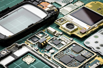 Microchips, semiconductor components and precious metals on the Board of the disassembled old mobile phone close-up on a green background