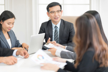 Fototapeta premium A confident business team of mixed ages and ethnicity are holding a meeting in a modern office. They are discussing ideas for their business development.In selective focus on face.