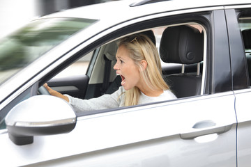 Hübsche blonde Frau schreit währen des Autofahrens entsetzt