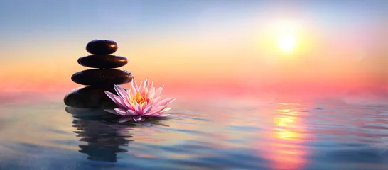 Foto auf Acrylglas Zen Zen-Konzept - Spa-Steine und Seerose im See bei Sonnenuntergang