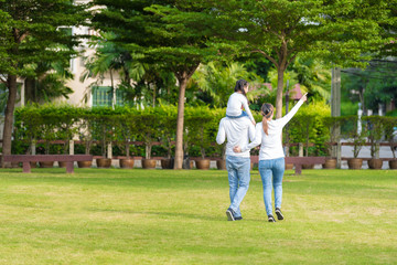 Cute Asian girl on neck parents big happy laughing and run around together.Happy family piggybacking adorable little daughter is smiling.