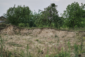 Mechanical excavation of earth using a excavator across the plain and the area with arable land