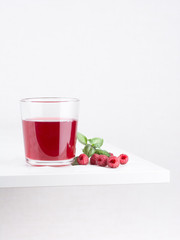 Fresh ripe raspberries and raspberry juice in a glass cup on a white background. Close-up, minimal concept of fashion food