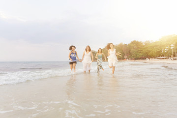 Summer of Happy girls running together on sunset sea beach. Holiday concept. Cinema film tone with grain.