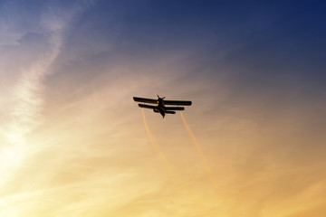 Fototapeta na wymiar Biplane flying in vibrant sunset