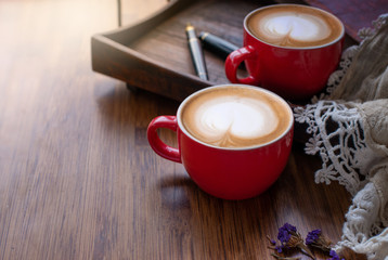 Two red coffee cups on a wooden tray and  scarf, on the wooden table