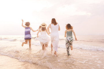 Summer of Happy girls running together on sunset sea beach. Holiday concept. Cinema film tone with grain.