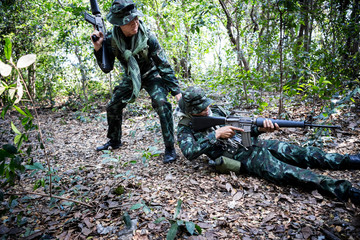 Asian army soldier with weapon during rescue operation evacuate injured fellow at across the deep forest.