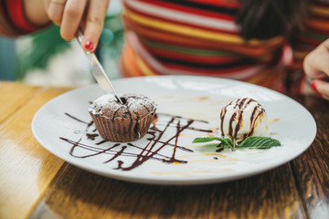 young adult woman eating chocolate fondant in cafe.