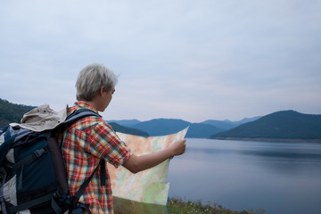 Fototapeta premium Young man trekker use map and enjoy traveling with backpack, hiking concept, travel concept