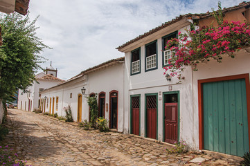 Fototapeta na wymiar View of cobblestone alley with old colorful houses and vegetation in Paraty, an amazing and historic town totally preserved in the coast of the Rio de Janeiro State, southeastern Brazil