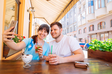 couple sitting in cafe in summer day taking selfie. cool drinks