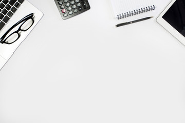 White office desk. table with blank notebook, tablet, calculator, computer and other office supplies. Top view with copy space.