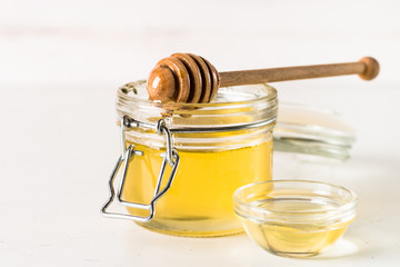 Honey  in a jar with dipper on white