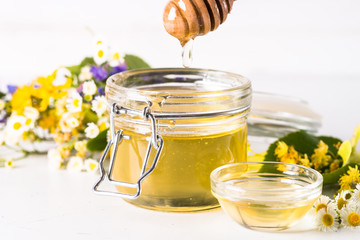 Honey  in a jar with wild herbs on white