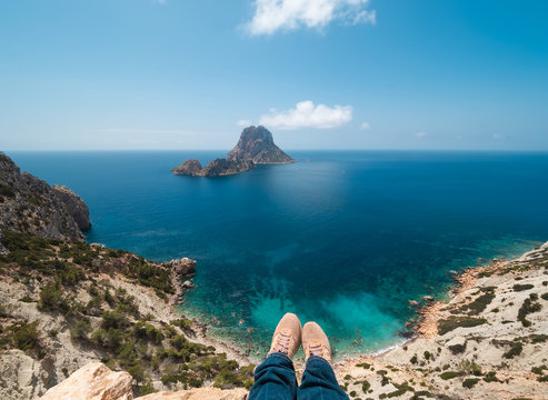 piernas y pies de mujer colgado de acantilado del parque natural de cala D&acute;hort. Al fondo se observan los islotes de Es Vedr&aacute; y Es Vedranell, Ibiza, Espa&ntilde;a
