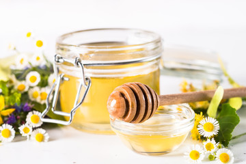 Honey  in a jar with wild herbs on white