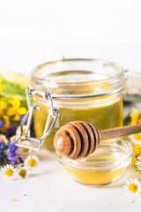 Honey  in a jar with wild herbs on white