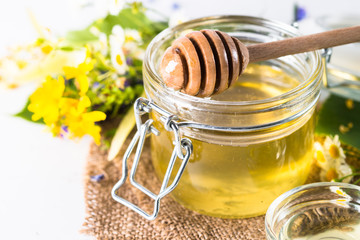 Honey  in a jar with wild herbs on white
