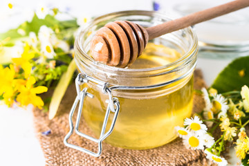 Honey  in a jar with wild herbs on white