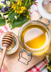 Honey  in a jar with wild herbs on white