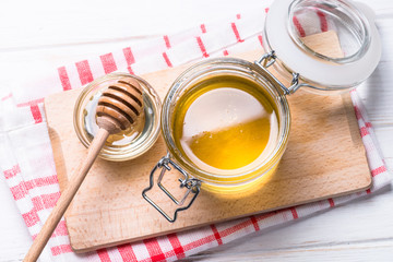 Honey  in a jar with dipper on white