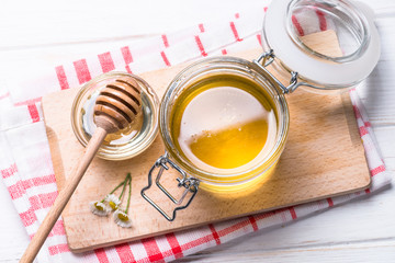 Honey  in a jar with dipper on white