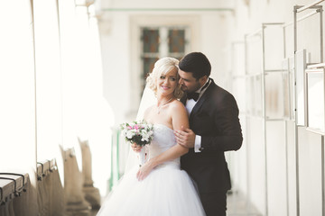 Lovely happy wedding couple, bride with long white dress posing in beautiful city