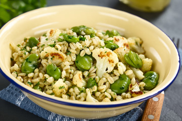 Fresh homemade vegan salad made of pearled barley, broad beans, roasted cauliflower and parsley...