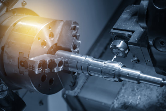 The CNC turning or lathe machine cutting groove slot at the brass shaft in the light blue scene by the milling spindle. Hi - technology manufacturing process.