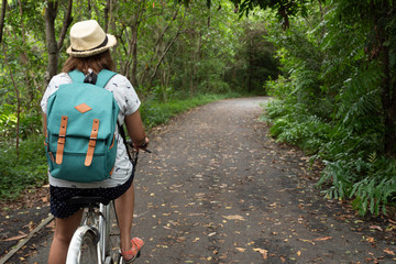 Woman riding a bike in in the green forest, relaxing time concept.