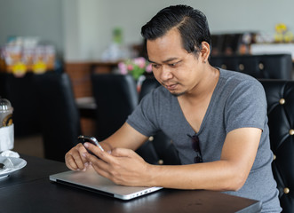 man using smartphone in a cafe