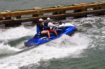 Man and a woman riding tandem on a blue and white jet ski on the florida intra-coastal waterway off Miami Beach.