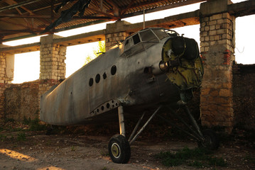 Old retro broken airplane in an abandoned hangar