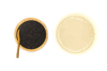 milk of sesame seed in ceramic with wooden bowl and spoon isolate on white  background. raw food diet and vegan concept with copy space