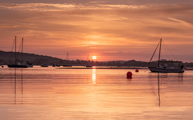 Sunset over River Exe Estuary at high tide with reflections of yachts