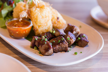 Grilled sticky rice with egg served with grilled diced steak with salad.