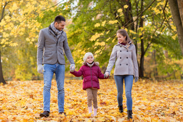 Naklejka na ściany i meble family, season and people concept - happy mother, father and little daughter walking at autumn park