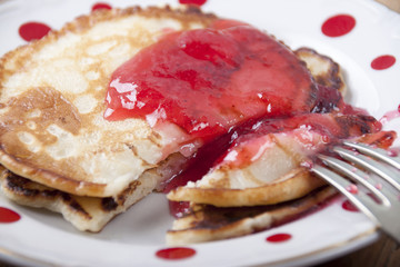Pancakes with red currant jam  in white plate in red peas