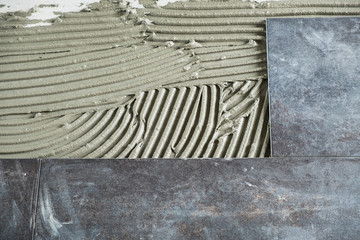  Dark grey ceramic floor tiles laid on applied adhesive