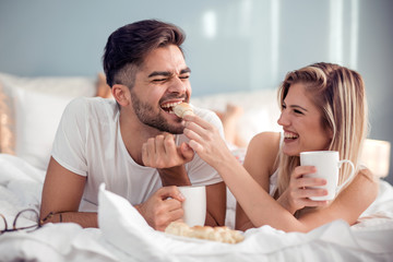 Young couple having a breakfast in the bed - obrazy, fototapety, plakaty
