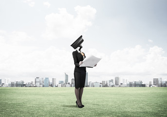 Camera headed woman standing on green grass against modern citys