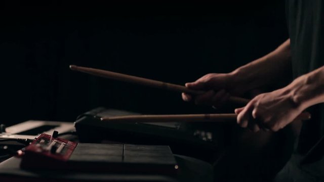 Close up slow motion shot of man drums sticks on sampler and electronic pads