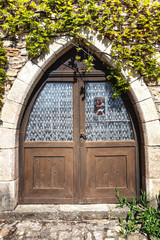 Fototapeta na wymiar Vieille porte en bois avec fenêtre en verre dans un mur de pierre 