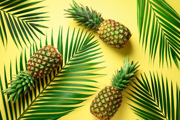 Pineapple and tropical palm leaves on yellow background. Top view. Summer concept. Creative flat lay with copy space.