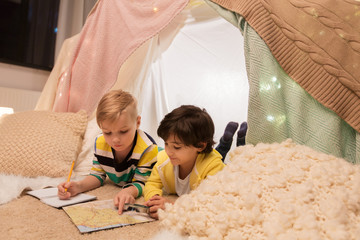 childhood, travel and hygge concept - happy little boys with magnifier and road map searching...