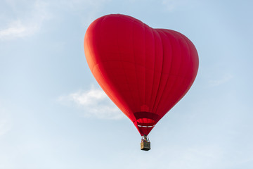 Red hot air balloon in the shape of a heart fly in sky. Love, honeymoon and romantic travel concept