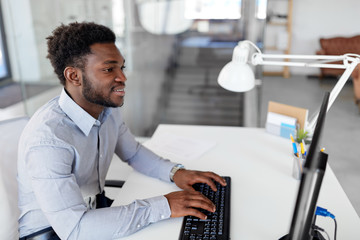 business, people and technology concept - african american businessman with computer working at office
