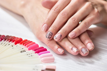 Girls hands with natural color manicure. Nude nails with black design. Female relaxation and care.